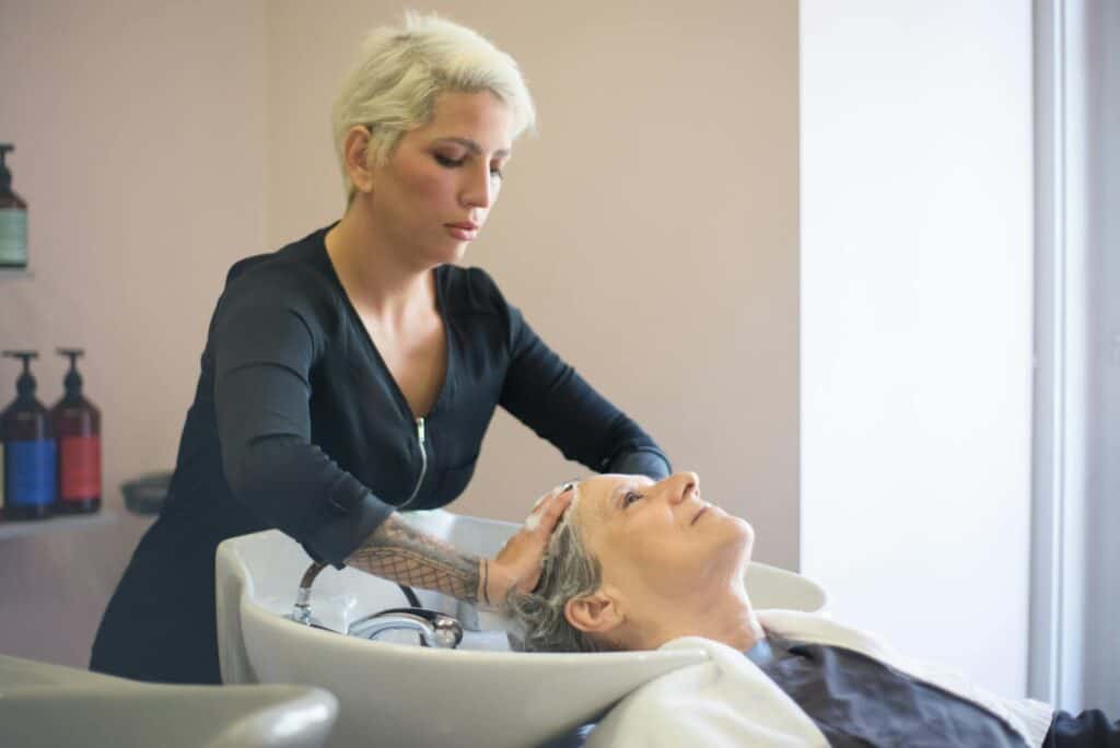 A hairdresser providing a relaxing hair wash to a senior woman in a salon setting.